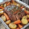 A tender, slow-roasted beef pot roast glazed in rich brown gravy, surrounded by golden baby potatoes and sweet carrots, and garnished with fresh parsley for a classic, comforting family dinner.